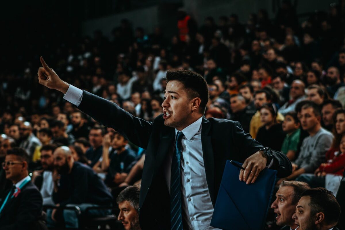 Motivated coach directing during a tense basketball game in a crowded arena.