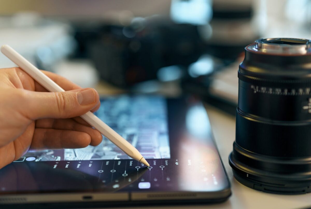 Closeup of a digital artist's hand using a stylus on a graphics tablet in a creative workspace.