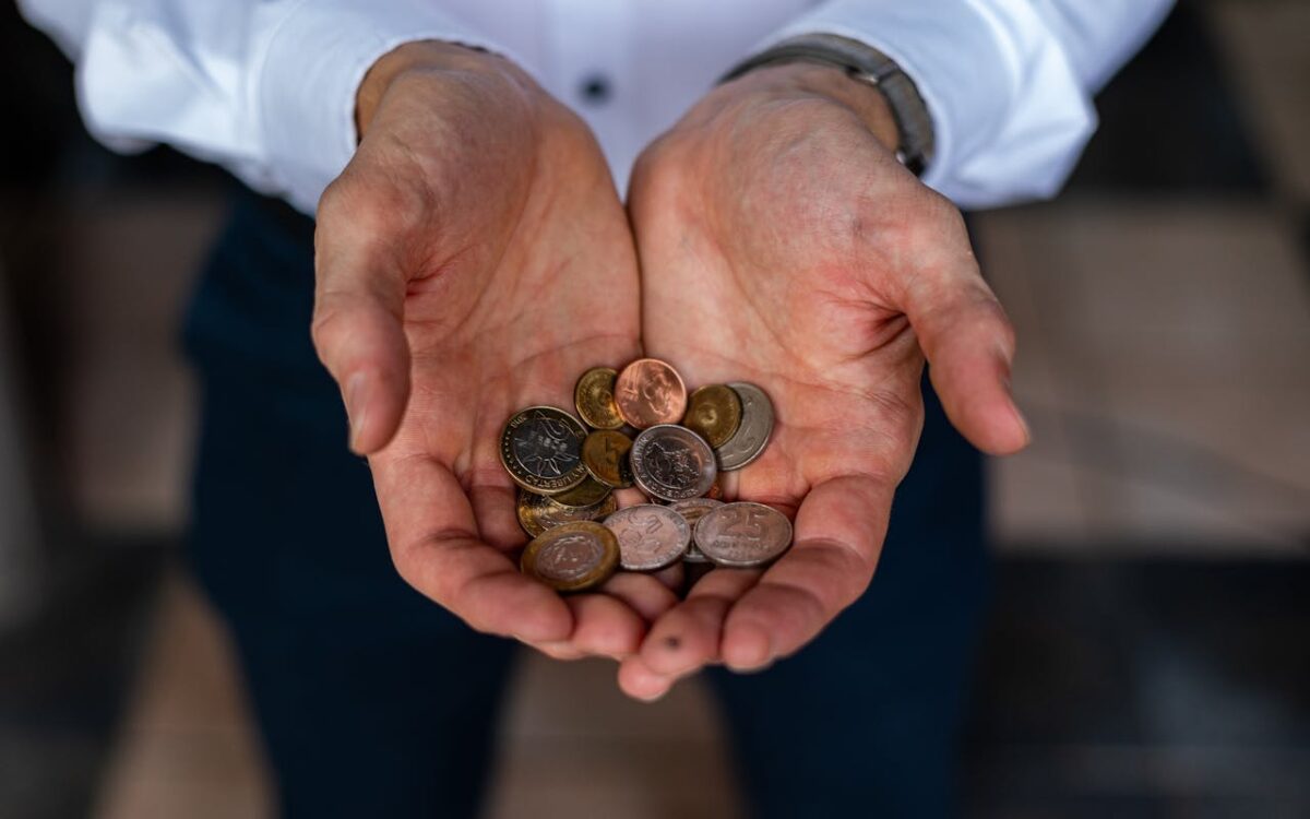 Closeup of hands holding various Argentine peso coins, symbolizing currency and finance in Argentina.
